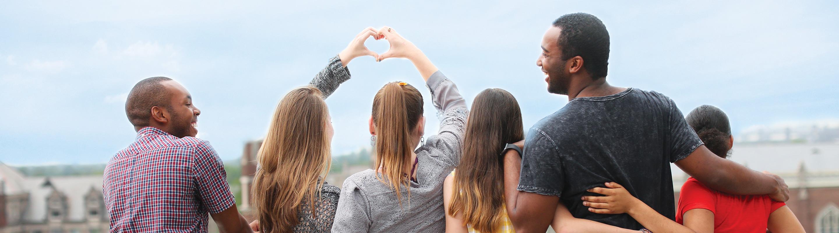 Six students, arm in arm, overlooking neighborhood